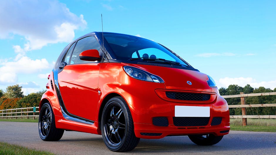 Red compact car parked outdoors on a bright sunny day showcasing stylish design and alloy wheels.