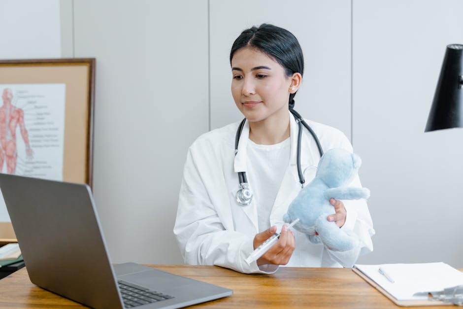 Female doctor using a laptop for an online consultation, demonstrating with a syringe and toy.