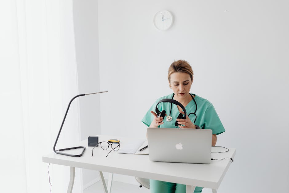 Female doctor in scrubs using a laptop for telehealth consultation in modern office setting